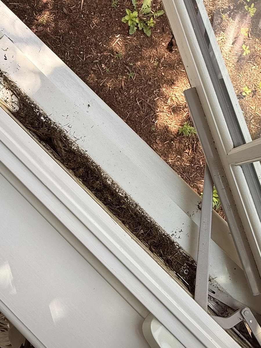 Window sill and track before cleaning — channel packed with dirt and debris