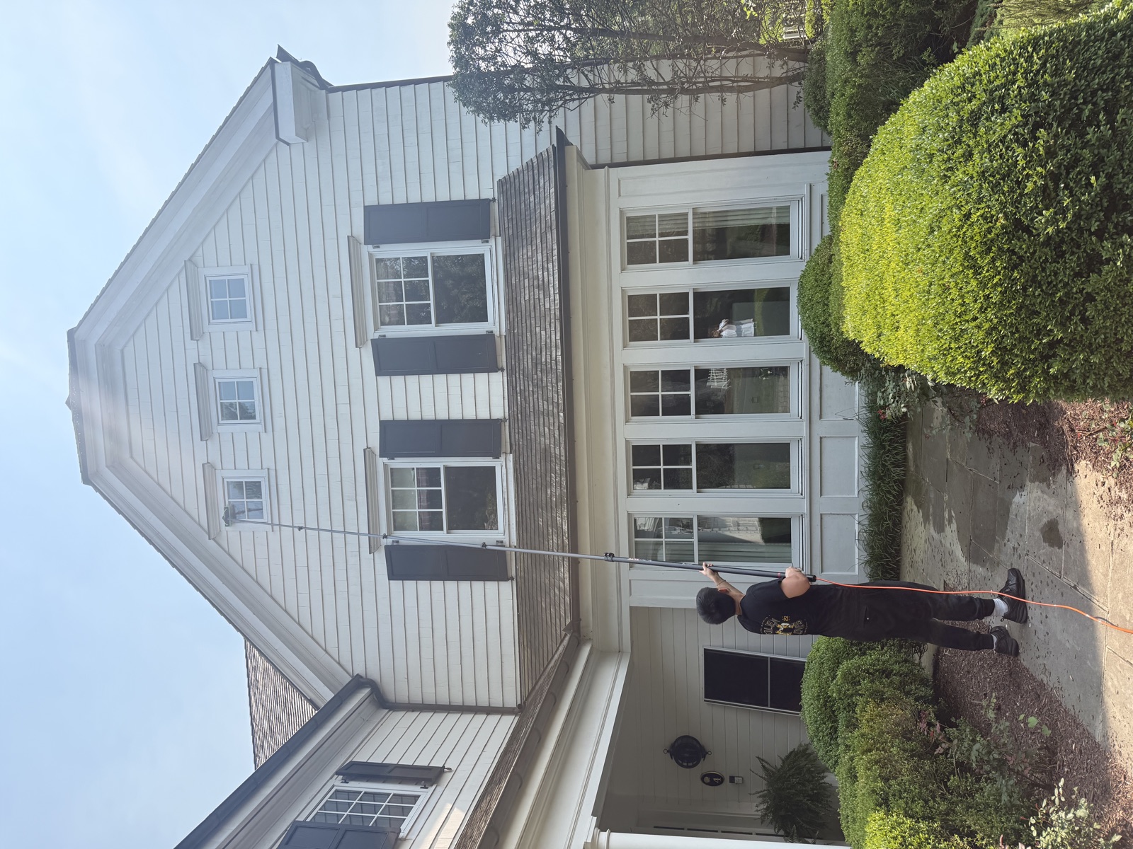 Clear View crew cleaning a white gambrel home's windows with water-fed pole, CT