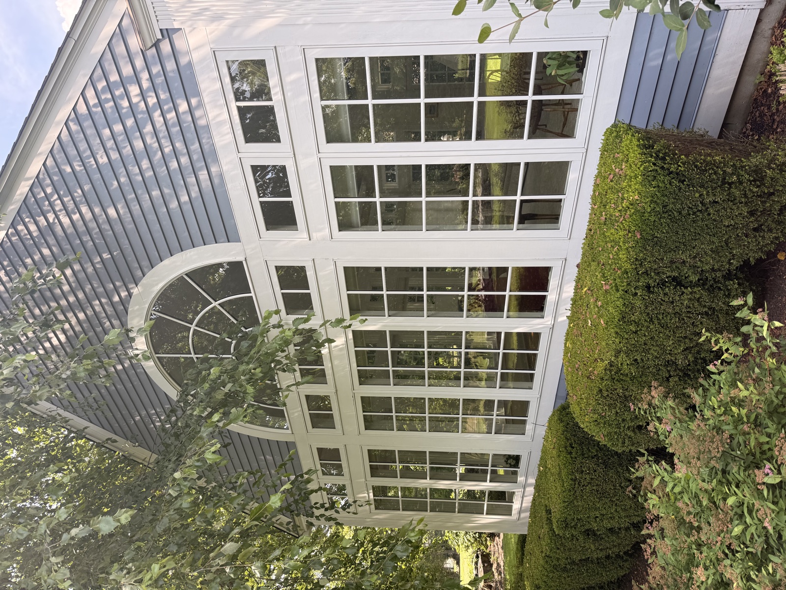 Blue-shingle Connecticut sunroom with arched window cleaned by Clear View