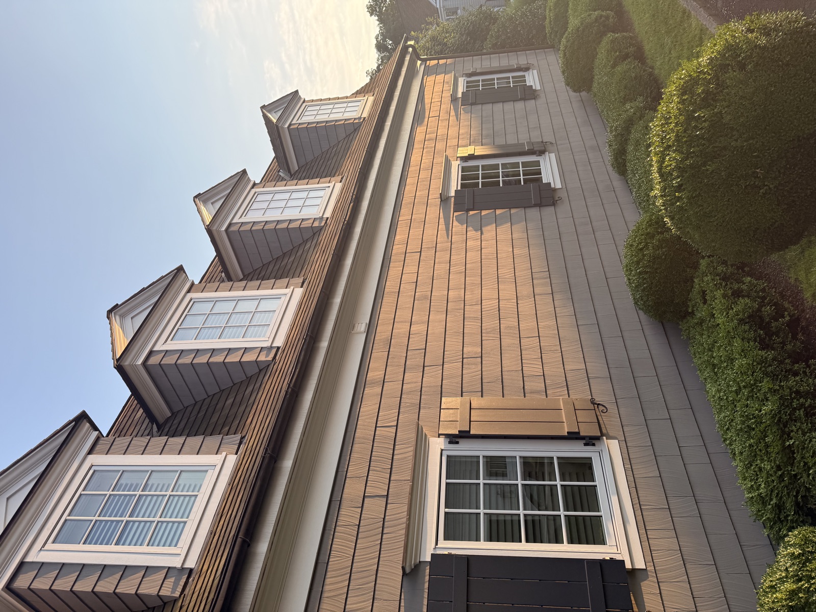 Cedar-shingle Connecticut home with clean dormer windows at sunset by Clear View
