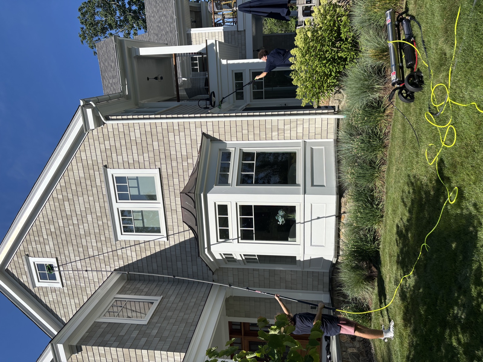 Clear View crew cleaning second-story windows with water-fed poles, coastal Connecticut home