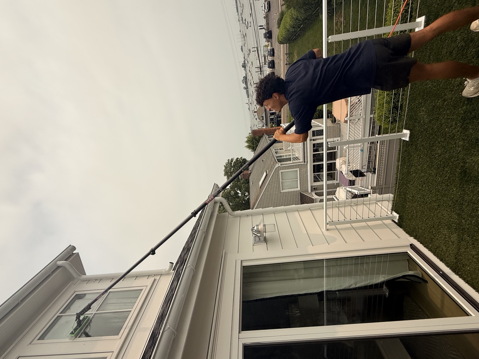Clear View technician cleaning upper windows above a deck, coastal Connecticut