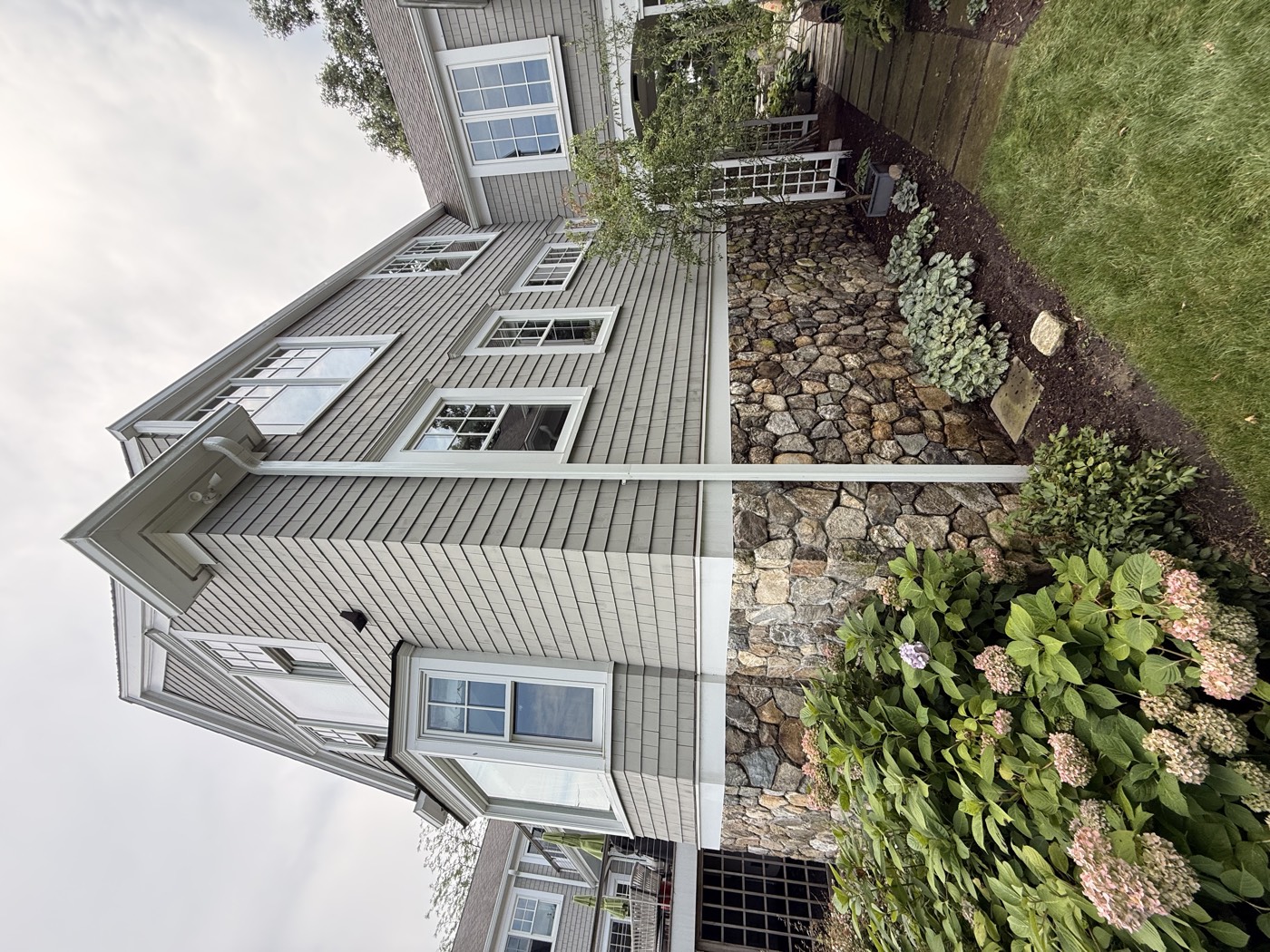 Side elevation of a gray shingle Connecticut home on a stone foundation, windows cleaned by Clear View