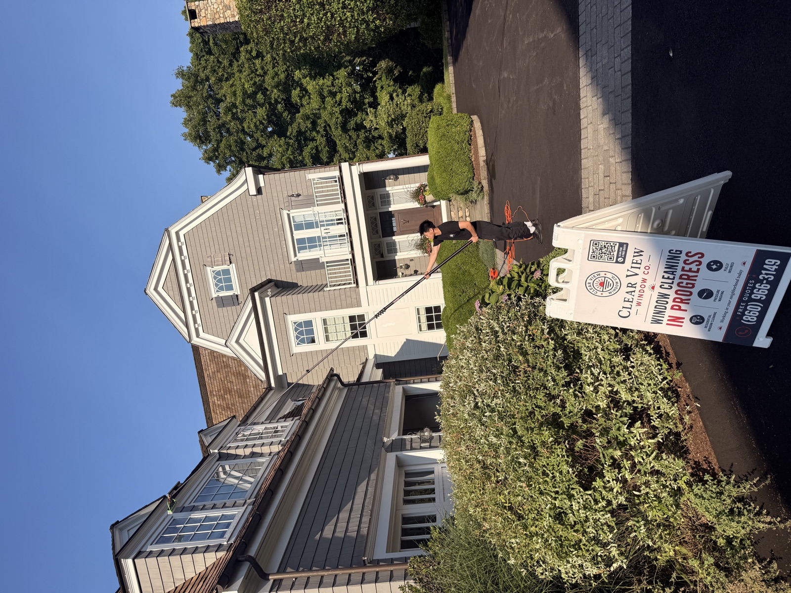Clear View Window Co. crew cleaning windows on a Connecticut home, branded job sign in front