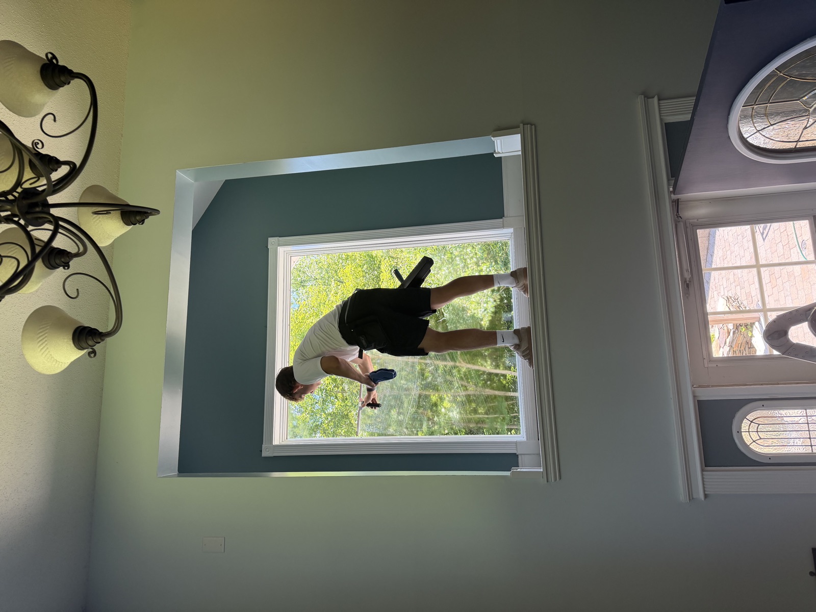 Clear View technician cleaning an interior picture window from the sill, Connecticut home