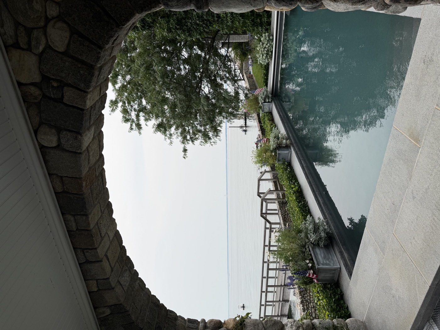 Stone archway framing a poolside view of Long Island Sound at a Connecticut shoreline home cleaned by Clear View