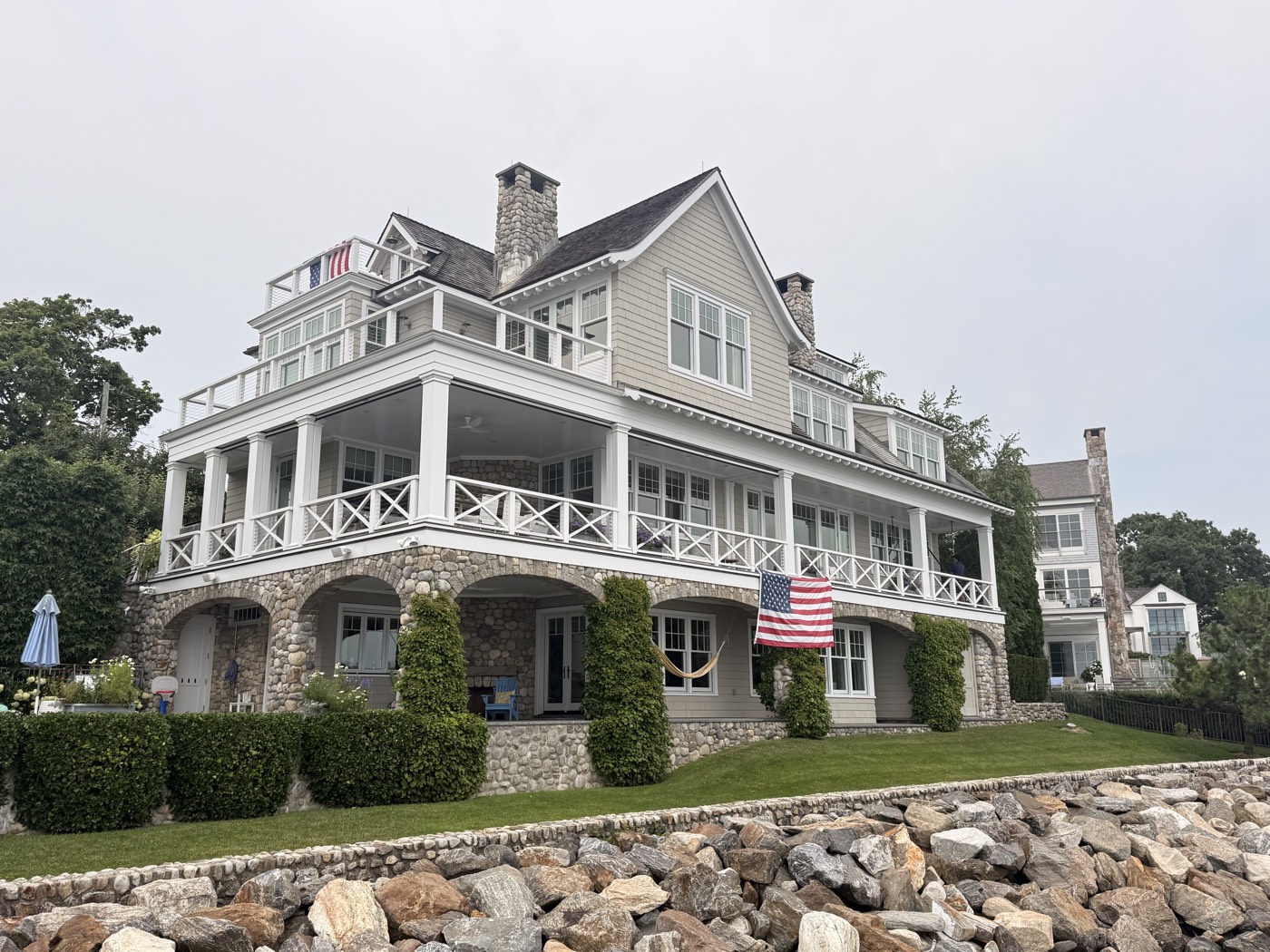Wide view of a Connecticut shoreline home with wraparound porch and seawall, windows cleaned by Clear View