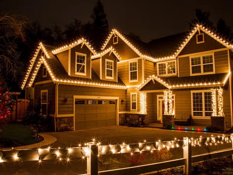 Nighttime photo of a Connecticut home with professional warm-white Christmas lighting along every roofline and a lit walkway