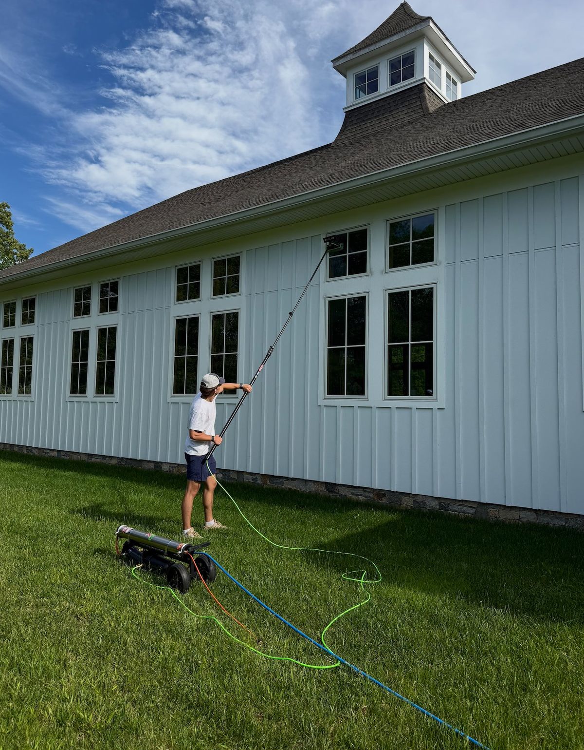 Clear View technician cleaning windows with a water-fed pole on a New England home